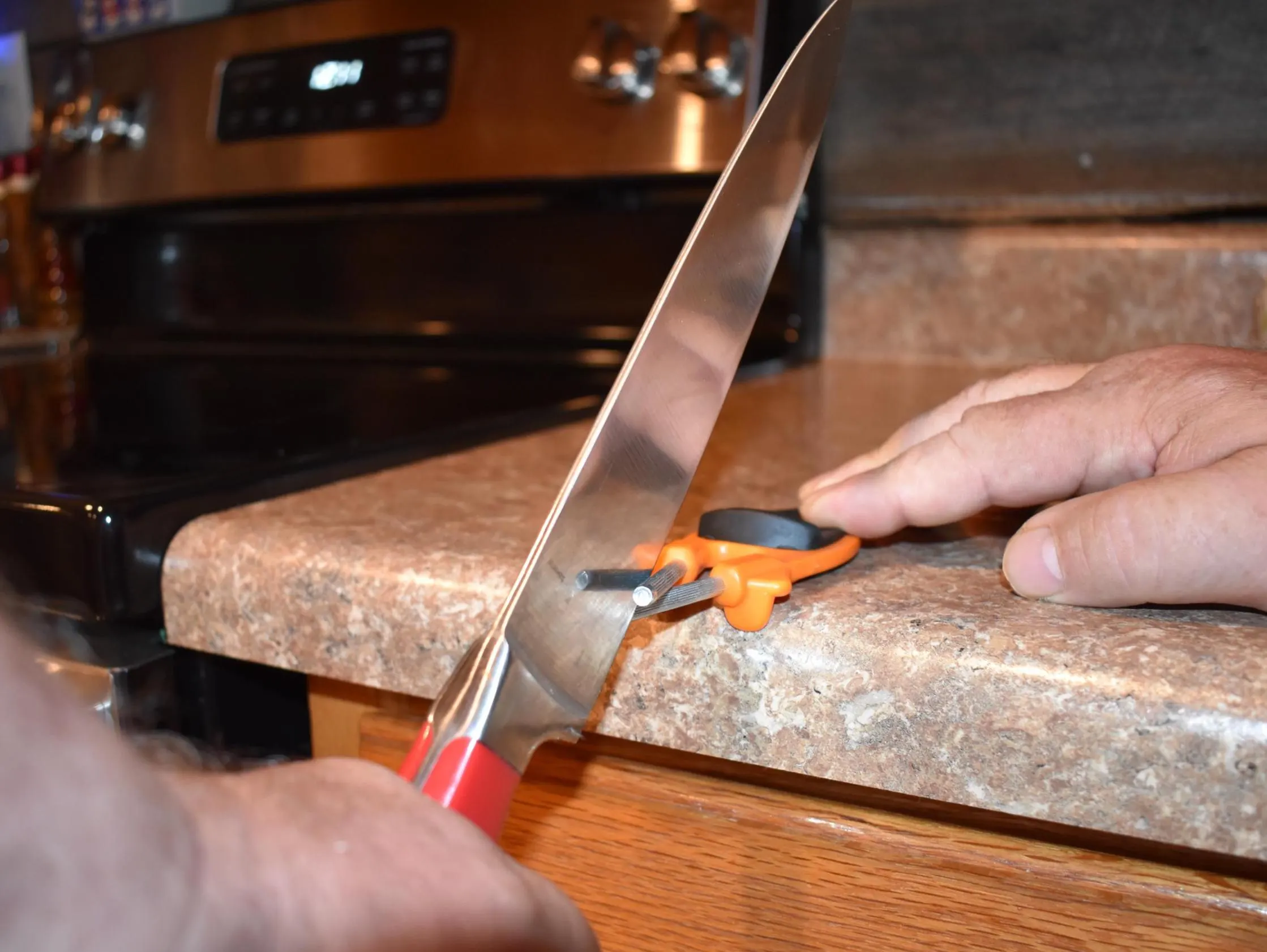 Hunting knife being sharpen on a orange Block sharpener